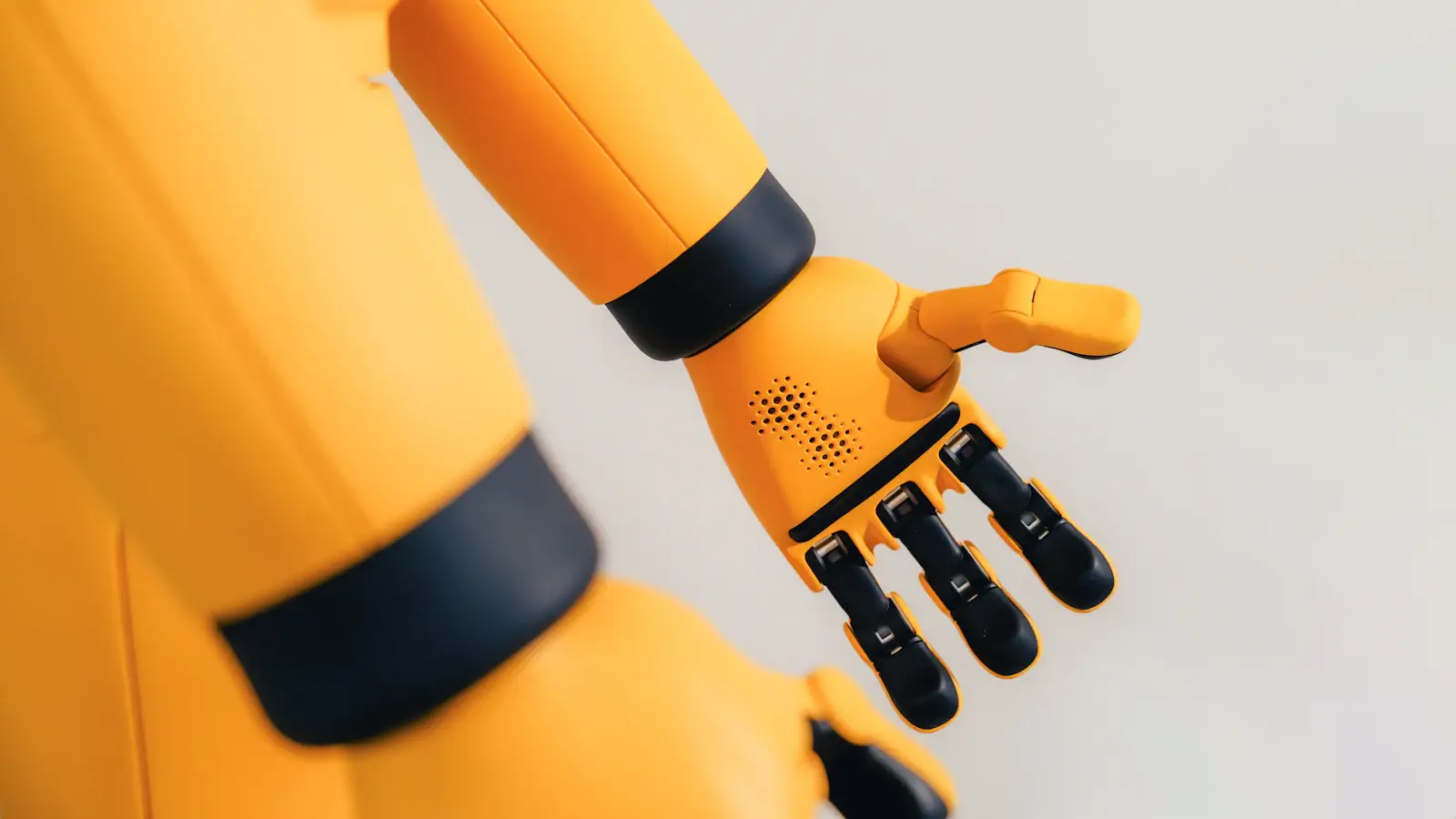 Yellow robotic arm with a mechanical hand, evoking AI agents that make payments autonomously