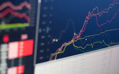 Close-up of a monitor displaying financial charts, representing transaction monitoring and AML screening