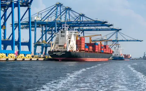 Large cargo ship beside a port crane, the trade flows settled in stablecoins between businesses