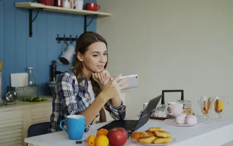 Smiling woman on a video call from her kitchen, staying connected with family abroad