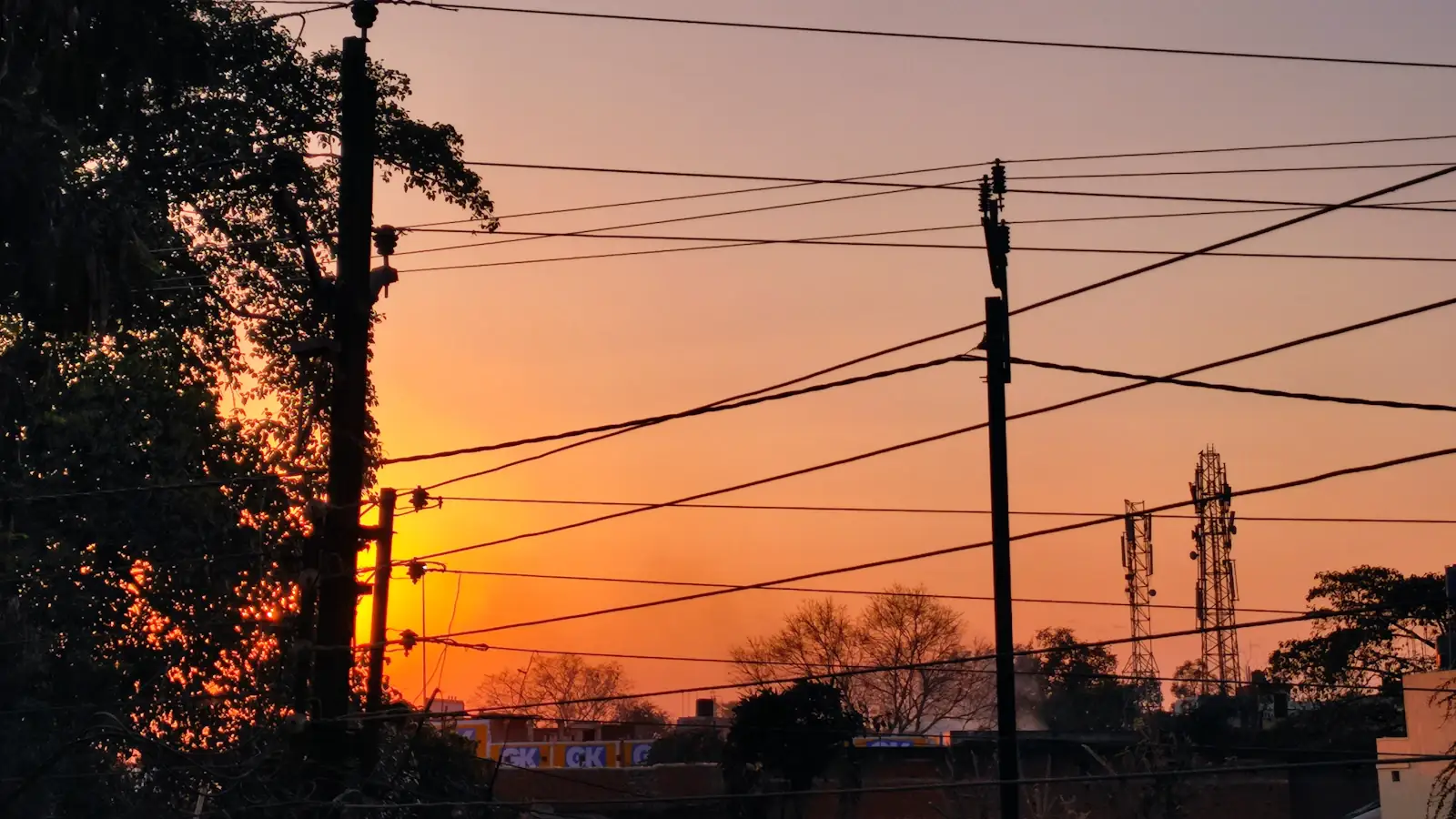 Warm sunset glowing behind power lines and poles in Chhattisgarh, India, household electricity supply