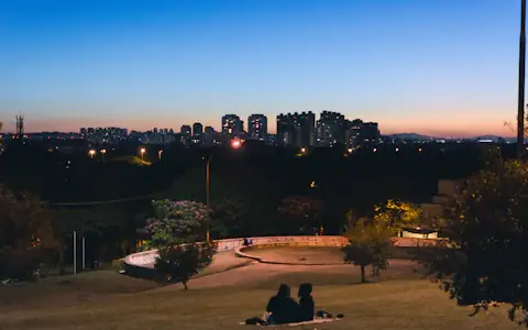 People relaxing on the grass at dusk overlooking the São Paulo skyline, Brazil