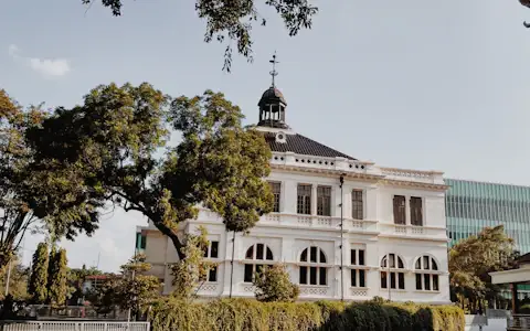 White colonial-era central bank building framed by green trees in Indonesia