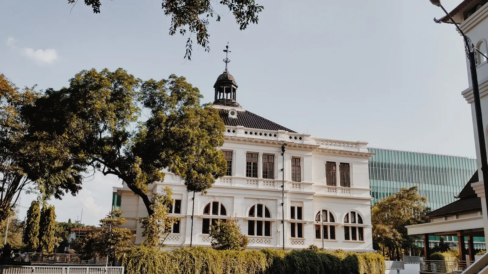 White colonial-era central bank building framed by green trees in Indonesia
