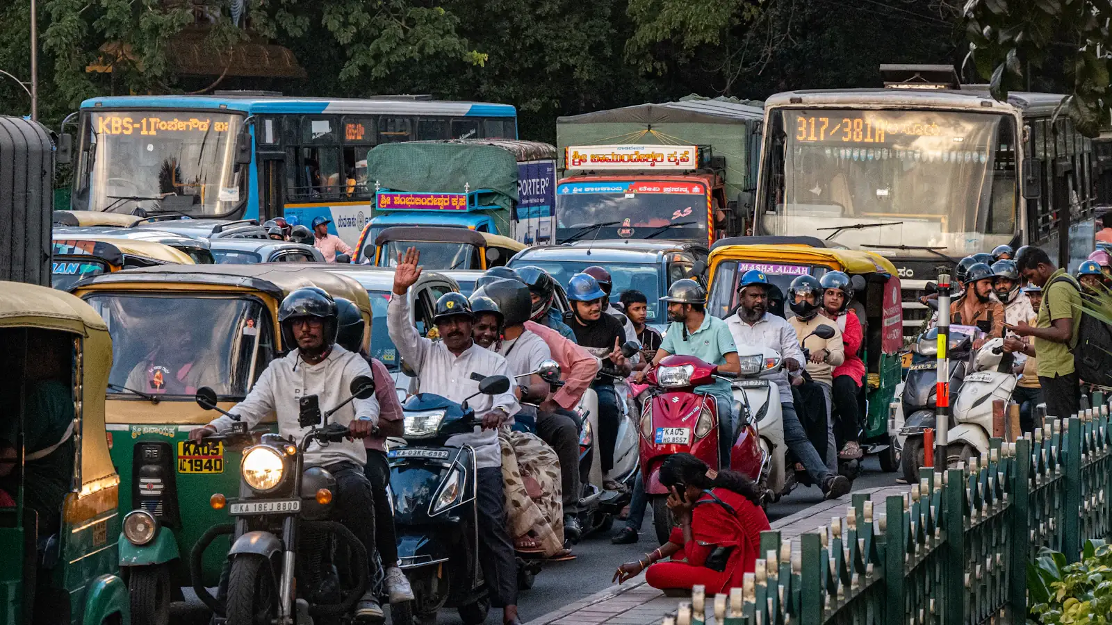 Busy Bangalore street with buses and scooters under green trees, where traffic e-challans apply