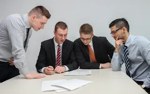 Four colleagues reviewing financial papers together around an office table