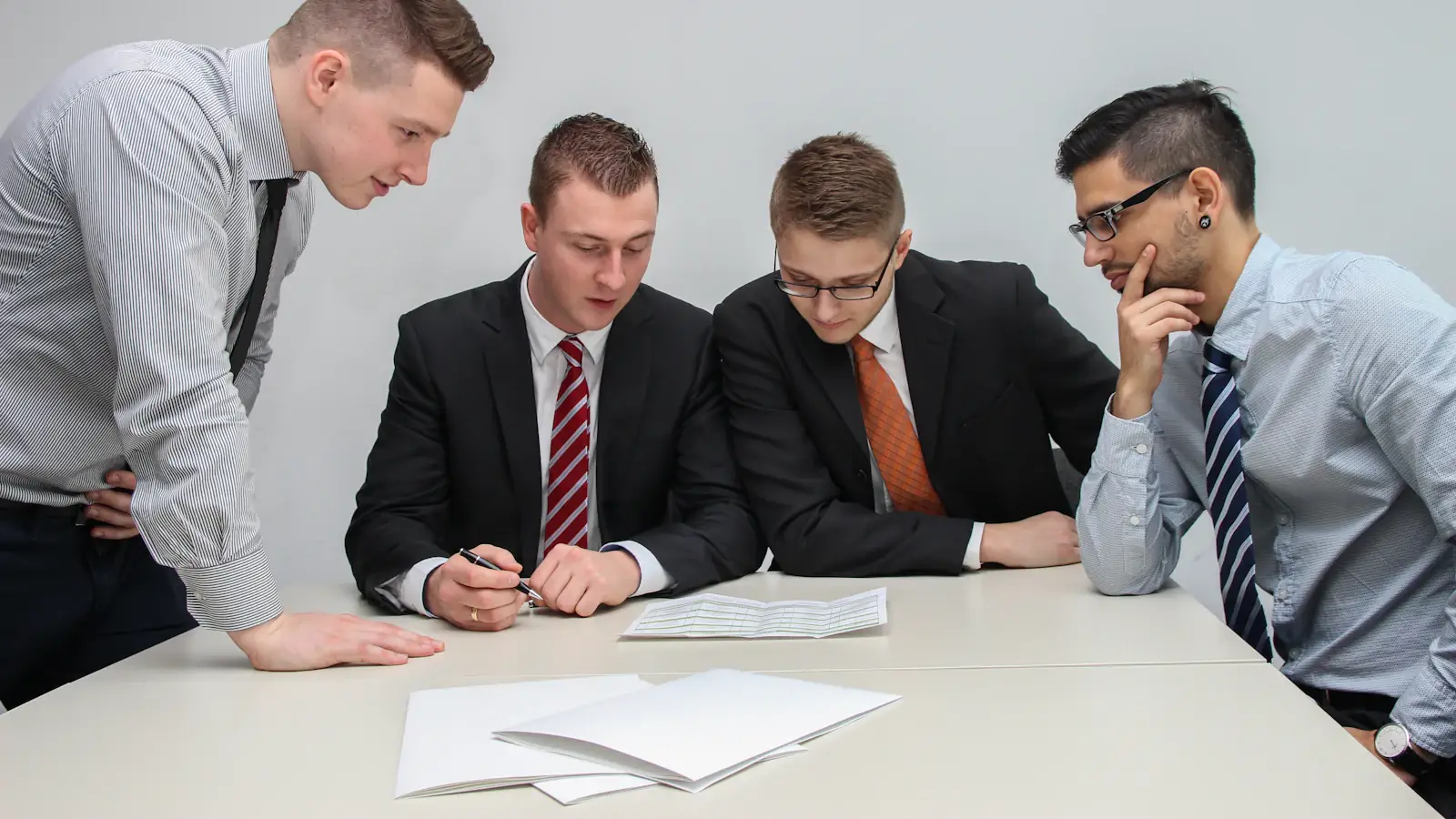 Four colleagues reviewing financial papers together around an office table