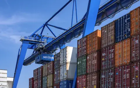 Stacked blue and red shipping containers at a port, the trade behind cross-border B2B payments