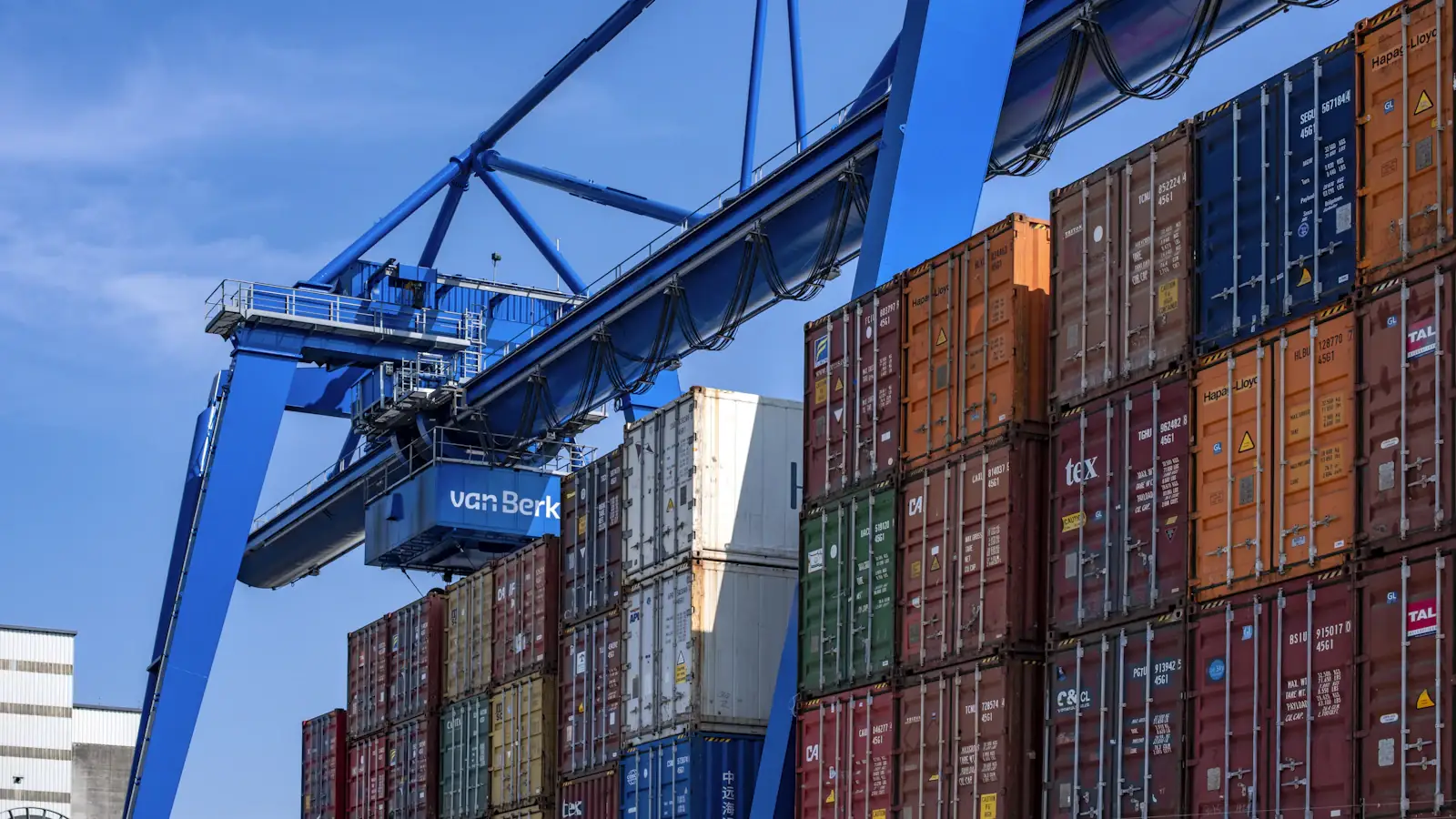 Stacked blue and red shipping containers at a port, the trade behind cross-border B2B payments