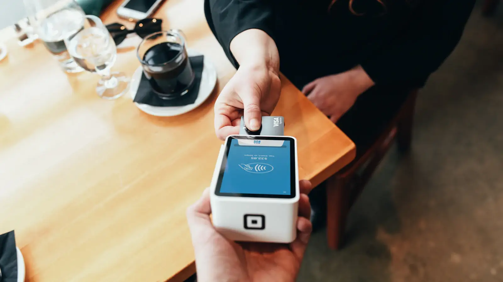 Hand holding a card payment terminal, showing how crypto and stablecoin cards are accepted