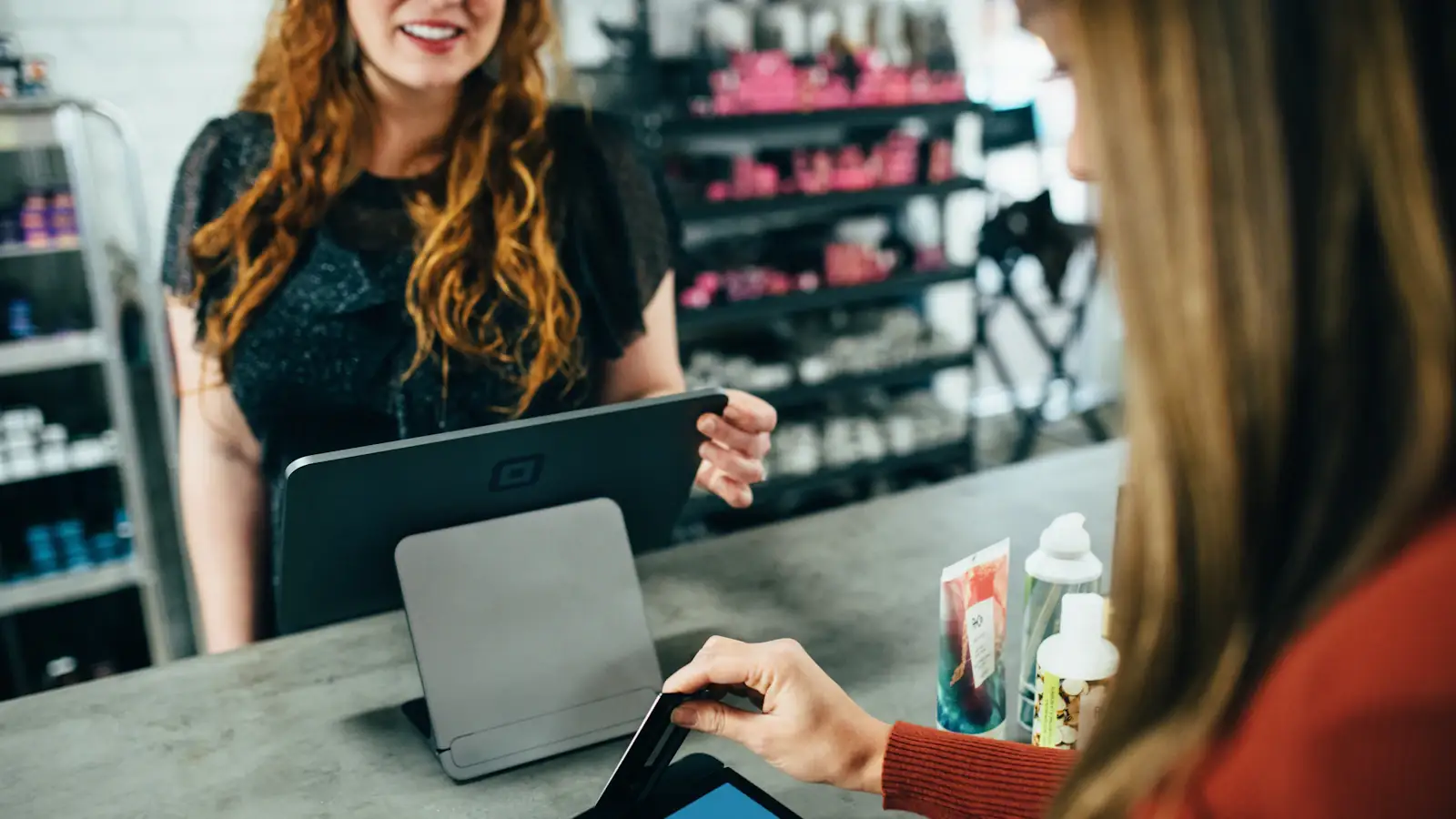 Woman holding a payment card at a shop counter, ready to pay with a crypto card