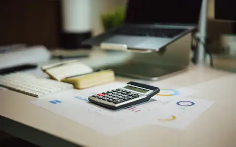 Calculator beside a laptop on a desk, ready for working out crypto tax across countries