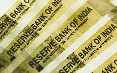 Stack of Indian rupee banknotes in warm light, the cash that India's digital rupee complements