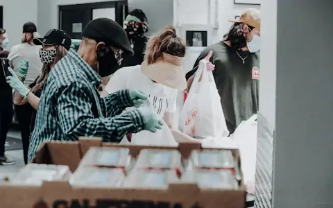 Volunteers standing beside stacks of cardboard aid boxes during a relief distribution effort