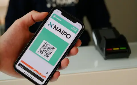 Person holding a smartphone in warm light, using a digital payment app