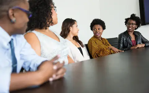 Diverse team of colleagues talking around an office table about benefits and cross-border pay