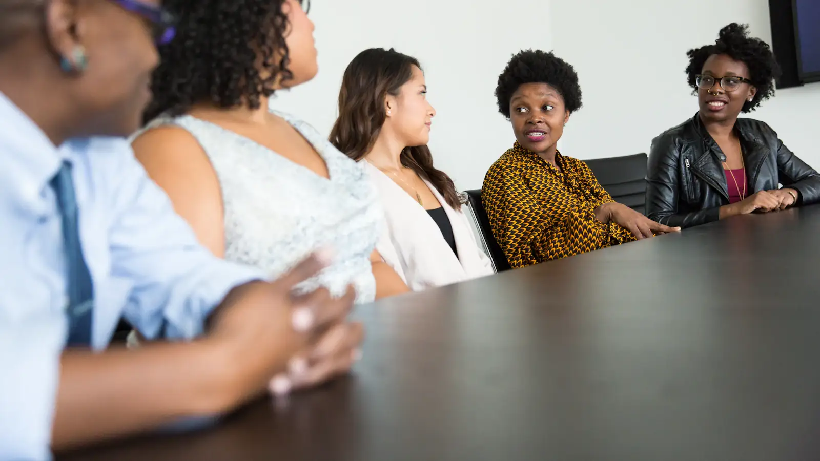 Diverse team of colleagues talking around an office table about benefits and cross-border pay