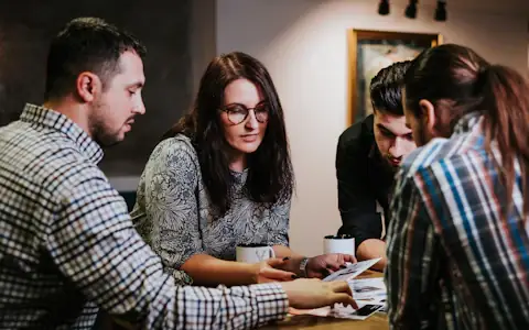 Four people reviewing documents at a wooden table, the compliance work behind the FATF Travel Rule