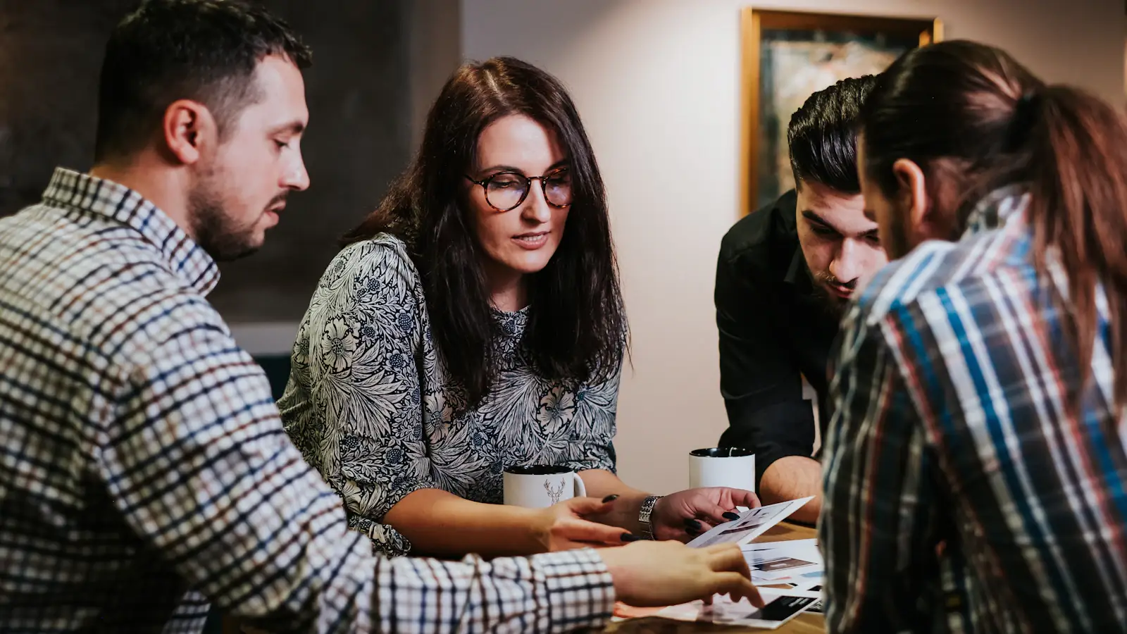 Four people reviewing documents at a wooden table, the compliance work behind the FATF Travel Rule