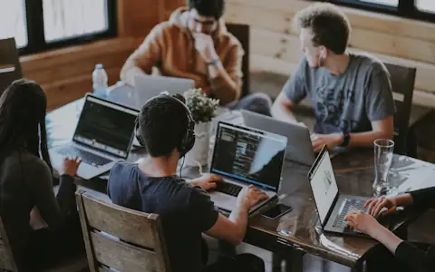 Fintech startup team collaborating around laptops at a shared table in a bright office