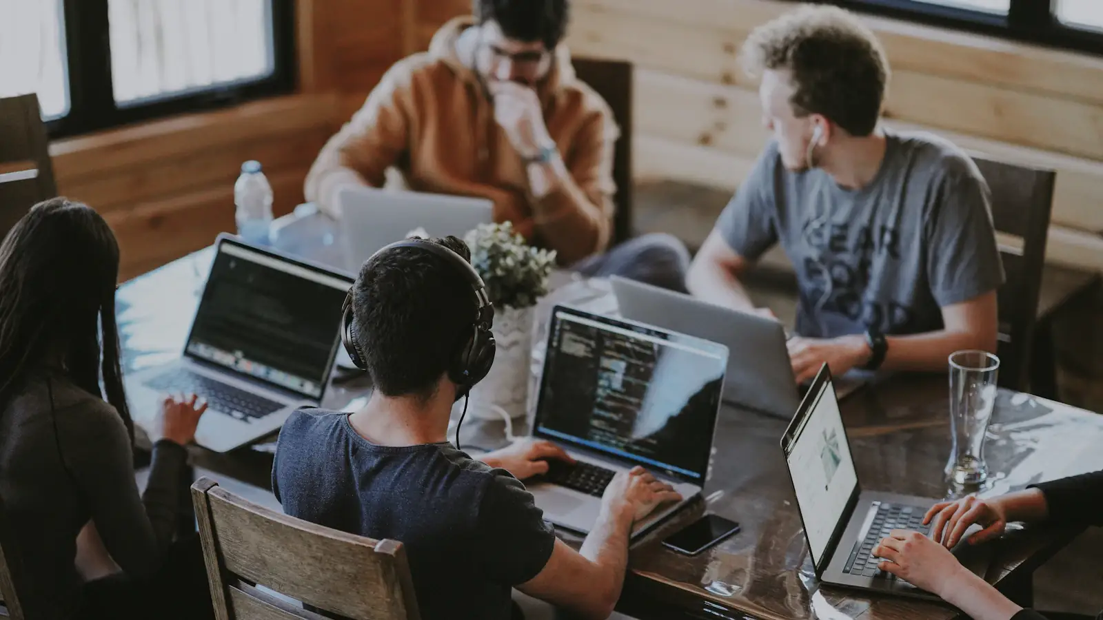 Fintech startup team collaborating around laptops at a shared table in a bright office