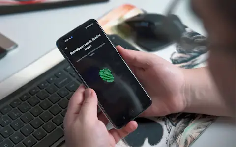 Person using the fingerprint sensor on a smartphone, the passkey-style security of self-custody wallets