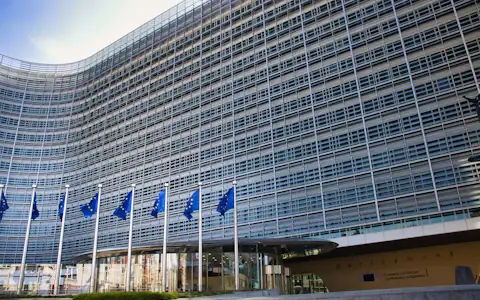 European Union flags flying outside a modern glass building, symbol of EU regulation
