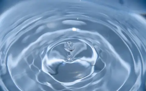 Single blue water droplet making a circular ripple, a small shock spreading outward