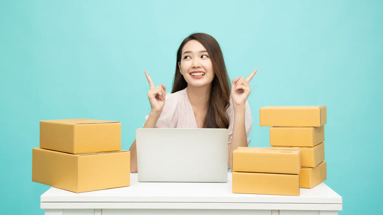 Small business owner working on a laptop surrounded by shipping boxes, managing business payments