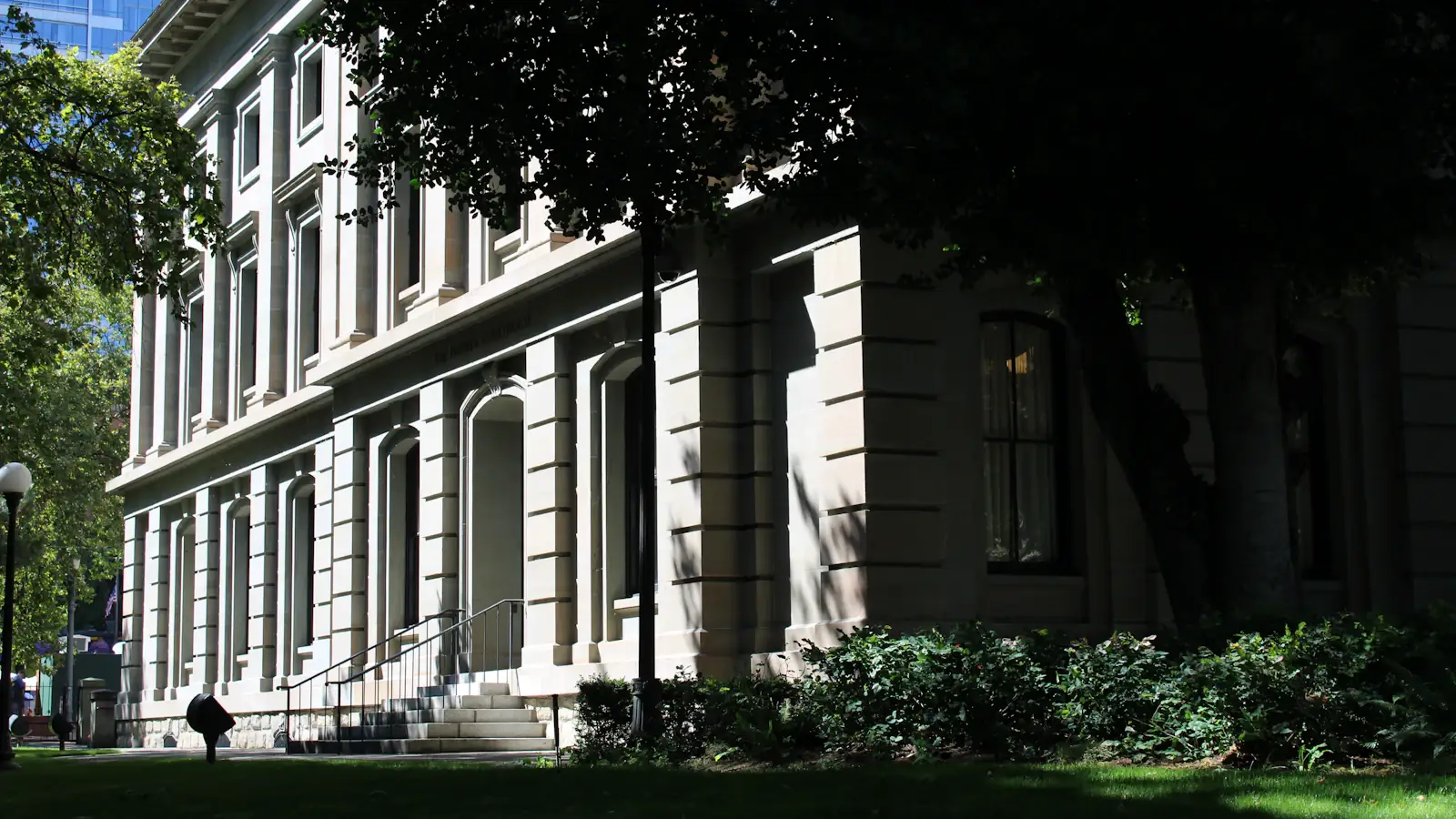 Historic sandstone courthouse framed by green trees, symbolising stablecoin law and regulation