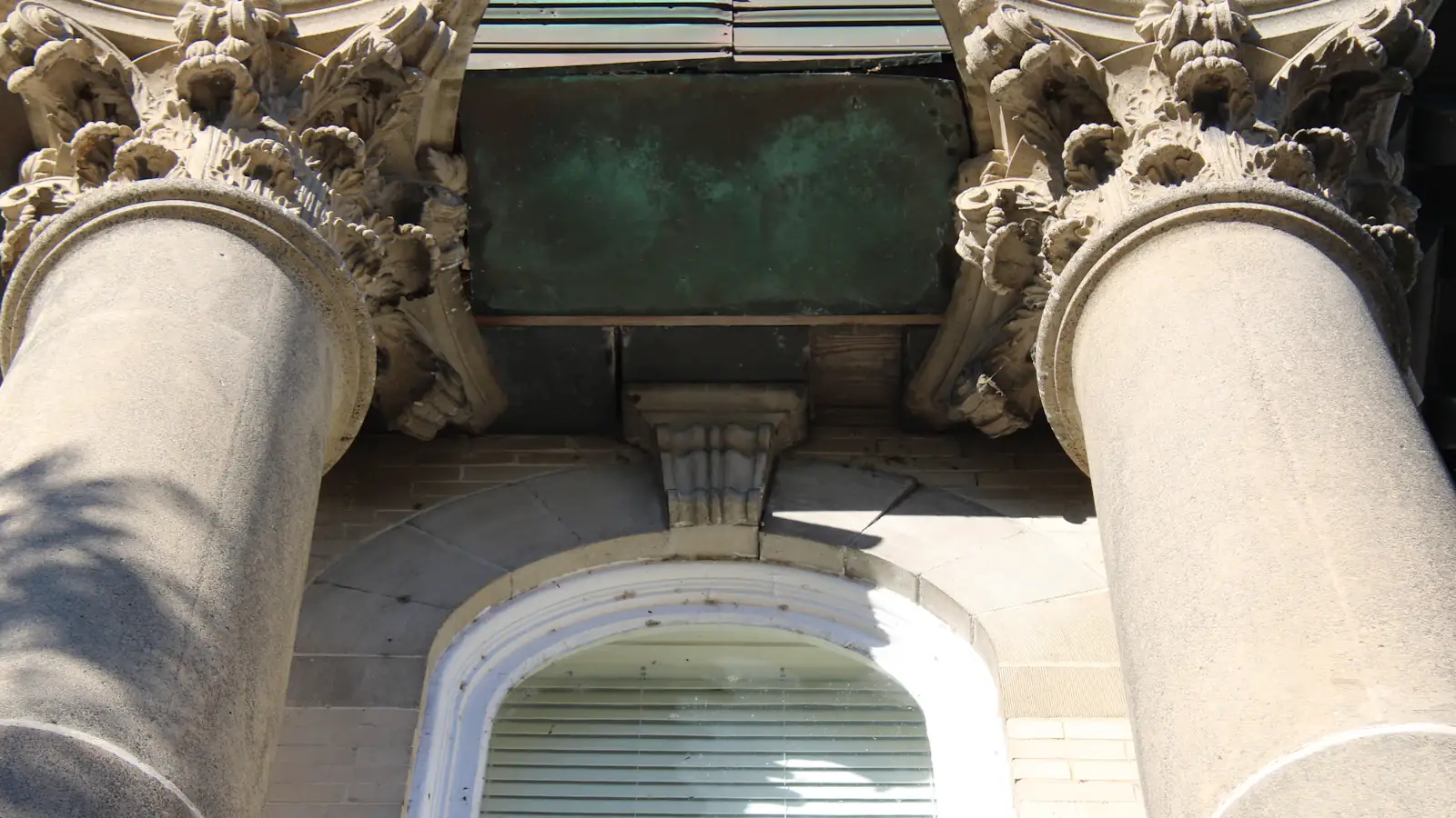 Tall stone bank building with classical columns seen from street level