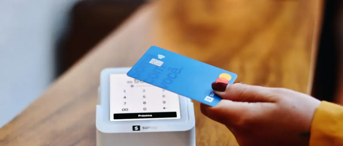 Customer holding a payment card at a terminal, the moment a crypto card is spent