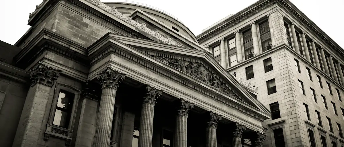 Grey stone columns of a classical building under bright light, a symbol of financial regulation