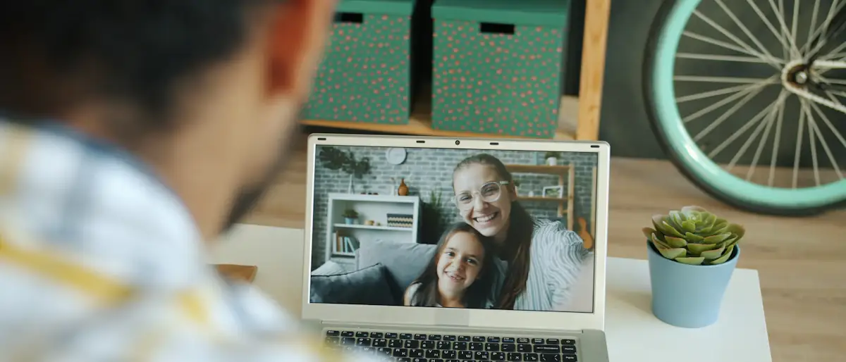 Man on a laptop video call waving to his family abroad, the people behind remittances