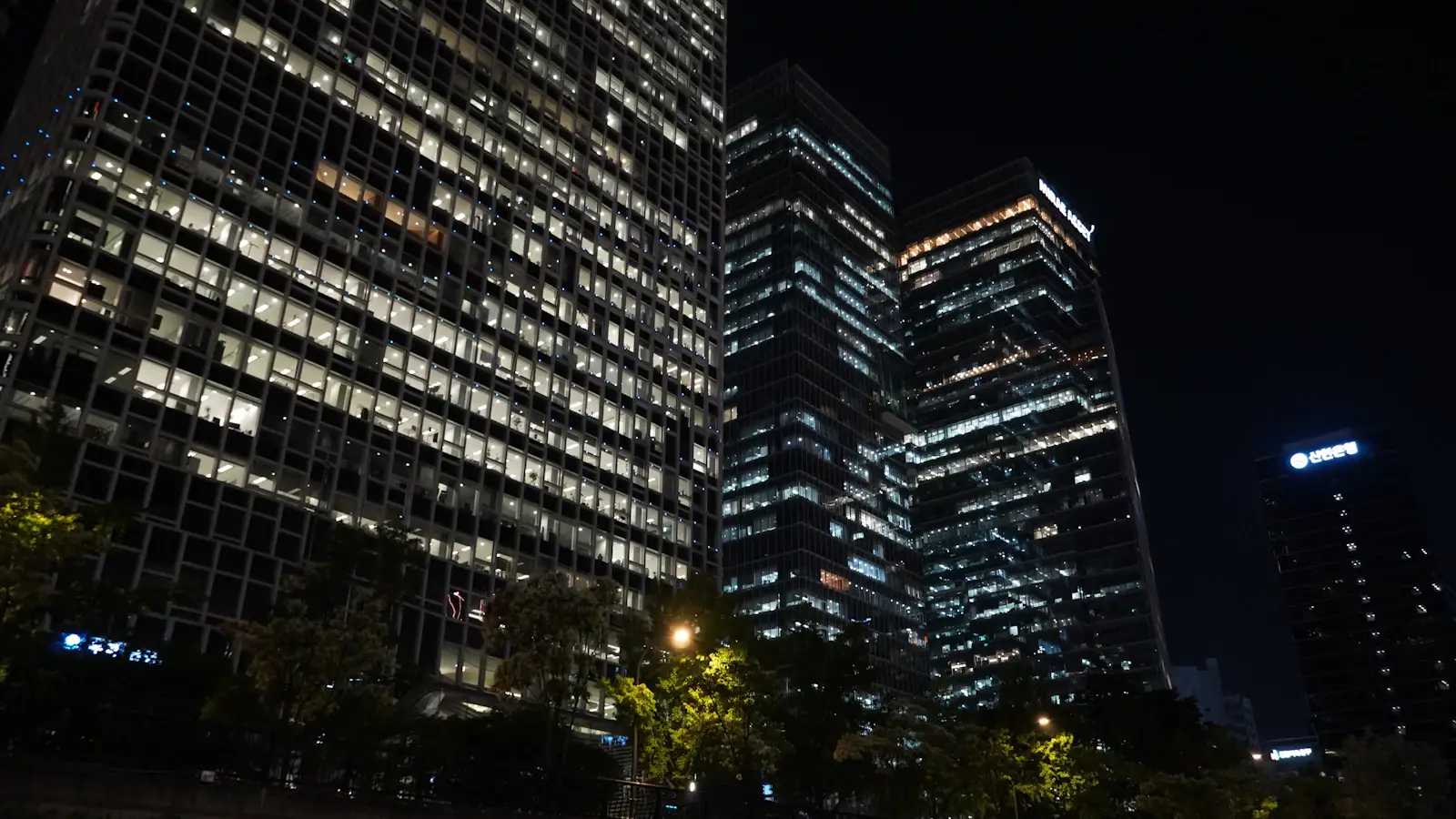 Bank office towers glowing at night, where wholesale CBDCs would settle payments between banks